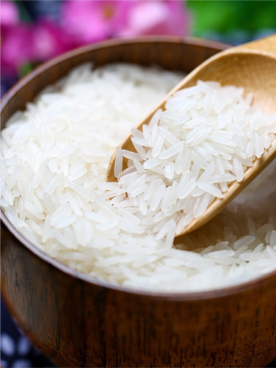 Jasmine rice in a wooden bowl with a scoop